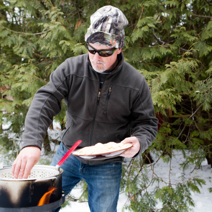 Scott Morrow in action cooking something on an outdoor-stove in winter