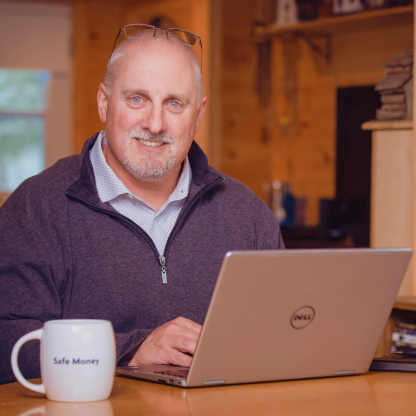 Scott Morrow working at his laptop, accompanied by a mug that says ‘Safe Money’