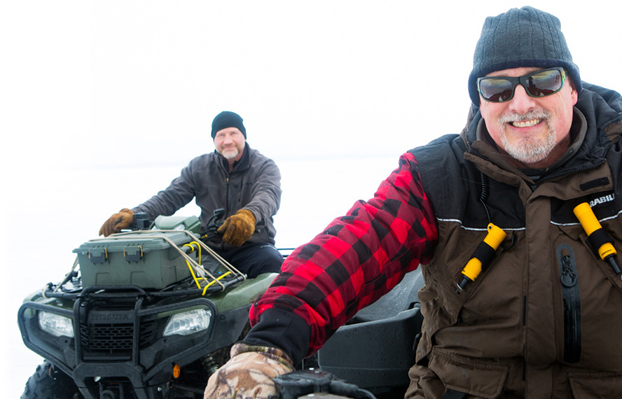 Scott Morrow four-wheeling with happy client Rob Daciw out on the lake in winter